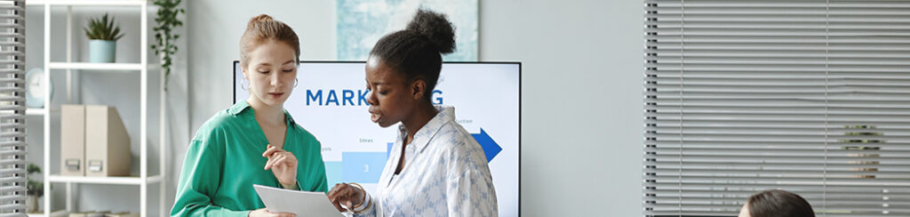 They discuss marketing budgets by industry with a presentation in a meeting