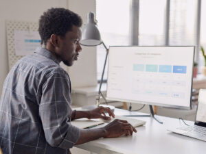He views a computer monitor on how to get blog traffic with a company comparison chart in a bright office.