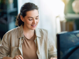 Woman smiling while researching Google Search vs Display Ads on her laptop in a bright indoor setting.