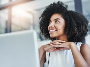 Woman smiling, looking up while updating her Google Profile for Business at her laptop.