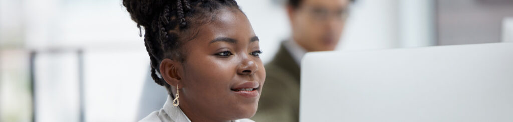 Woman with braided hair works on a website redesign at her computer in an office.