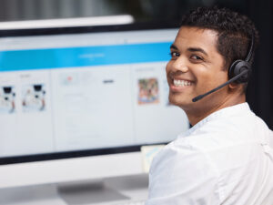 Man wearing a headset and white shirt smiles at his desk, ready to assist on your service area landing page for SEO.