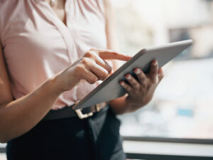 A person in a light blouse uses a tablet indoors, researching local SEO cost.