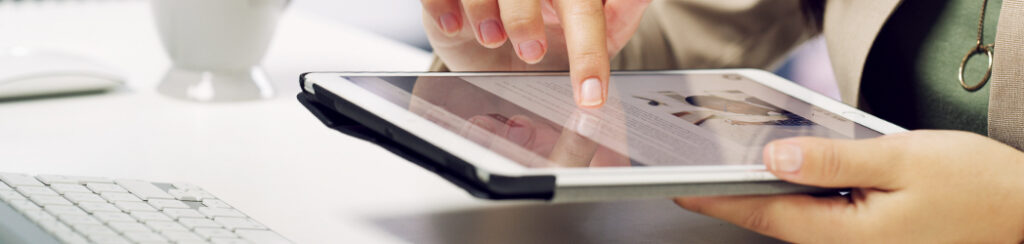 Hand using a tablet on a desk, exploring why local rankings benefit small businesses on the digital screen.