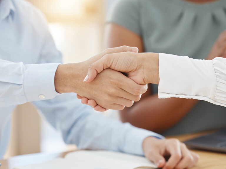 Two people shake hands across a table, highlighting the importance of reviews for local SEO.