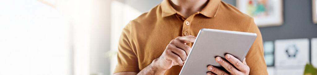 Person in a brown shirt using a tablet indoors, researching diy digital marketing.
