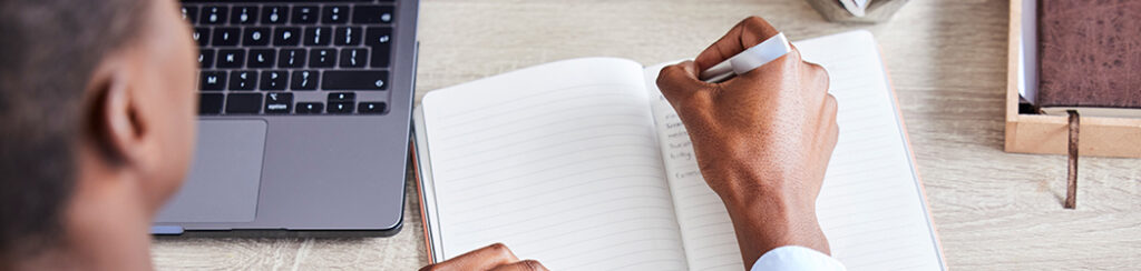 Person writes in a notebook beside a laptop, considering "do blog posts affect local seo?"