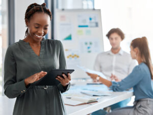 Woman uses a tablet to look up data on seo vs google ads during a meeting with colleagues