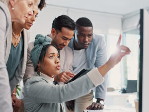 Five people discuss seo cannibalization, focused on a computer screen as one points out key details.