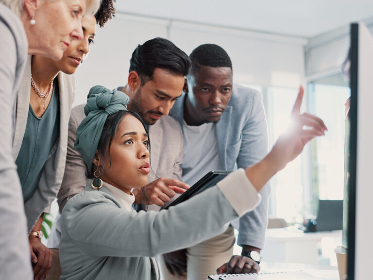 Five people discuss seo cannibalization, focused on a computer screen as one points out key details.