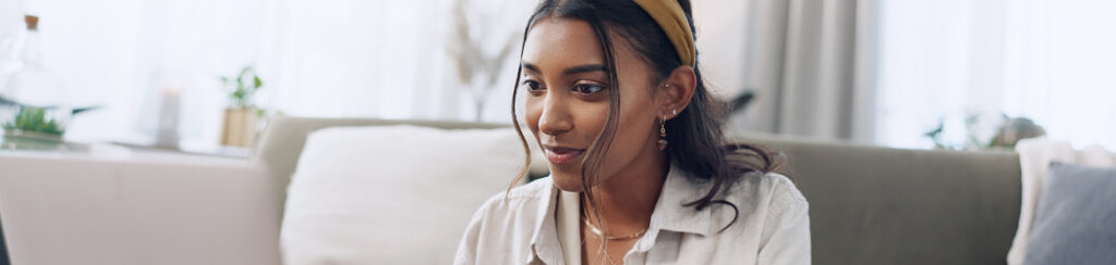 Woman wearing a headband sits indoors, viewing local SERPs on her laptop