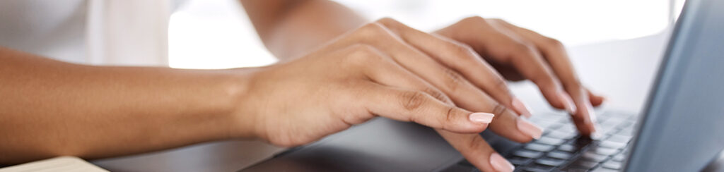 Hands typing on a laptop keyboard, with part of an on page seo checklist notebook visible nearby.