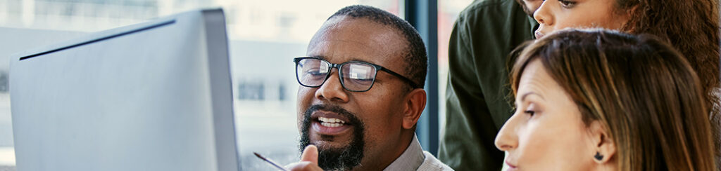 Four people gathered around a monitor, collaborating on a customer acquisition strategy displayed on the screen.