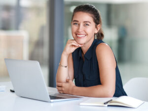 Woman sitting at a desk with a laptop, smiling as she reviews website performance.