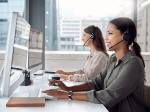 Two women wearing headsets boost website engagement while working at computers.