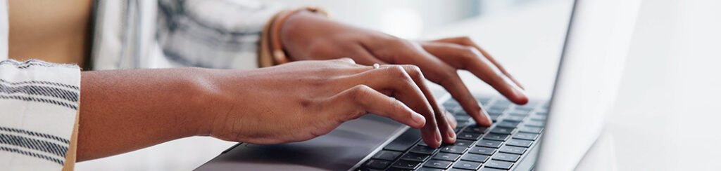 Hands typing on a laptop and working to identify website visitors
