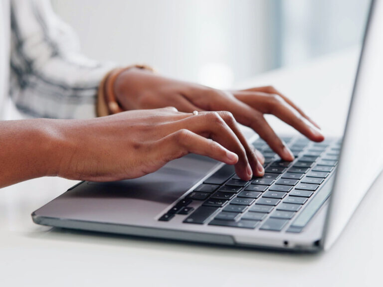 Close-up of hands typing on a laptop to identify website visitors