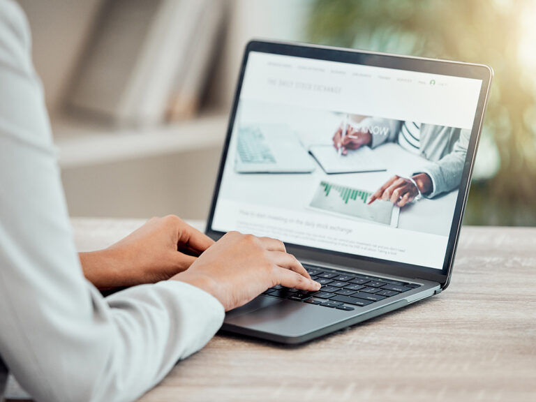 Person using a laptop, viewing local SEO landing pages about stock exchange and financial data.