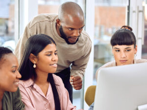 Four people discuss strategies at a computer, exploring why invest in local SEO services.