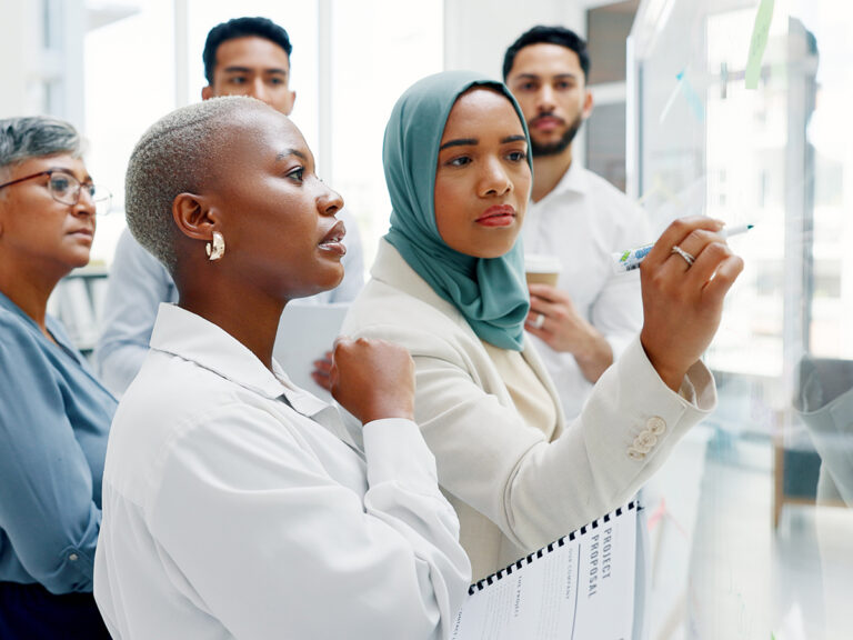 Small business colleagues discuss ideas for an SEO campaign at a glass board