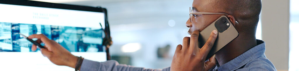 Man holding a phone to his ear and pointing at a computer screen while discussing SEO for Google My Business