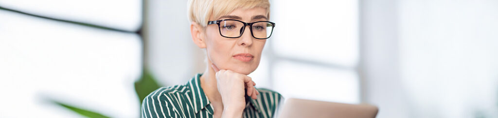 Woman thoughtfully reviews service pages that convert through her laptop screen.