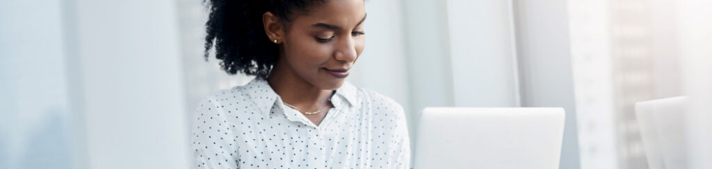 Woman with curly hair works on a laptop, using a blog as a lead generation tool.