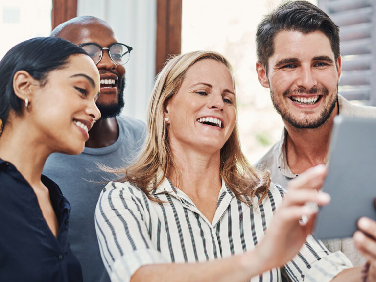 A business owner and her team smiling and viewing a tablet to see the business's Google reviews