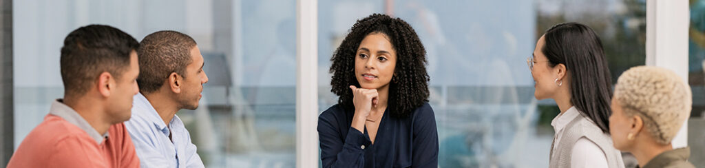 Five people sit together in discussion, with one woman in the center displaying a clear marketing mindset.