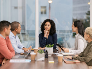 Five people meet around a table, collaborating with a marketing mindset in a modern office.
