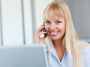 Woman with long blonde hair calling a local business after seeing their Google business profile page through her laptop