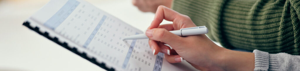 Close-up of a person holding a pen and reviewing a budget plan to ensure low budget marketing