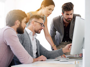 Small business team focuses on marketing consistency as they analyze data on a computer