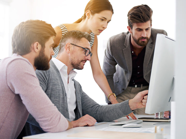 Small business team focuses on marketing consistency as they analyze data on a computer