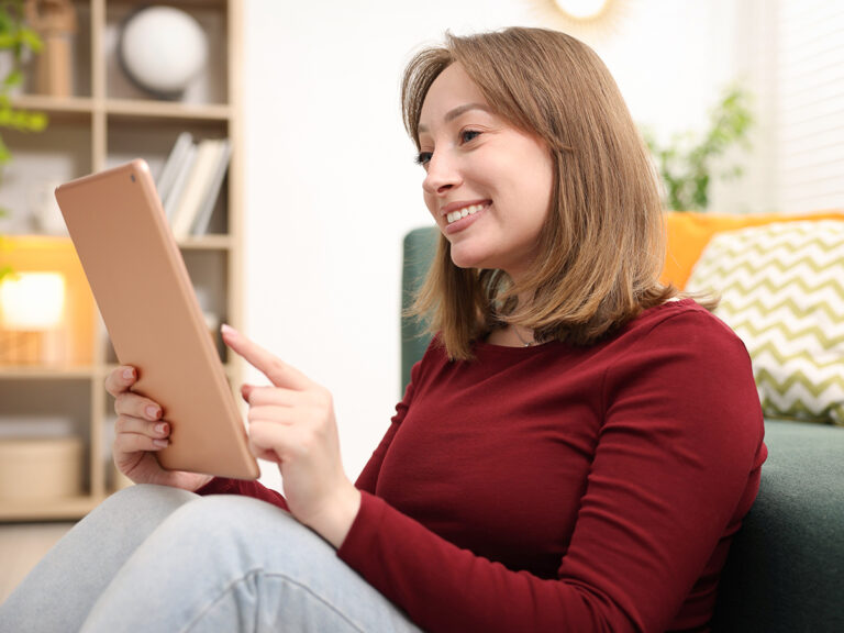 Woman smiling while looking at a tablet, viewing customer feedback and review response content.