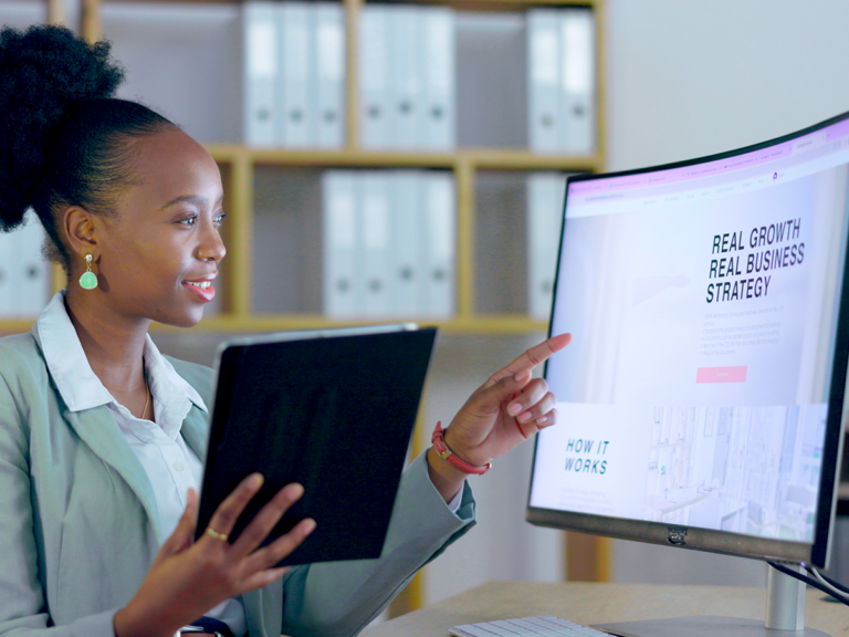 Woman viewing monitor and tablet showing real growth real business strategy, focused on brand storytelling.