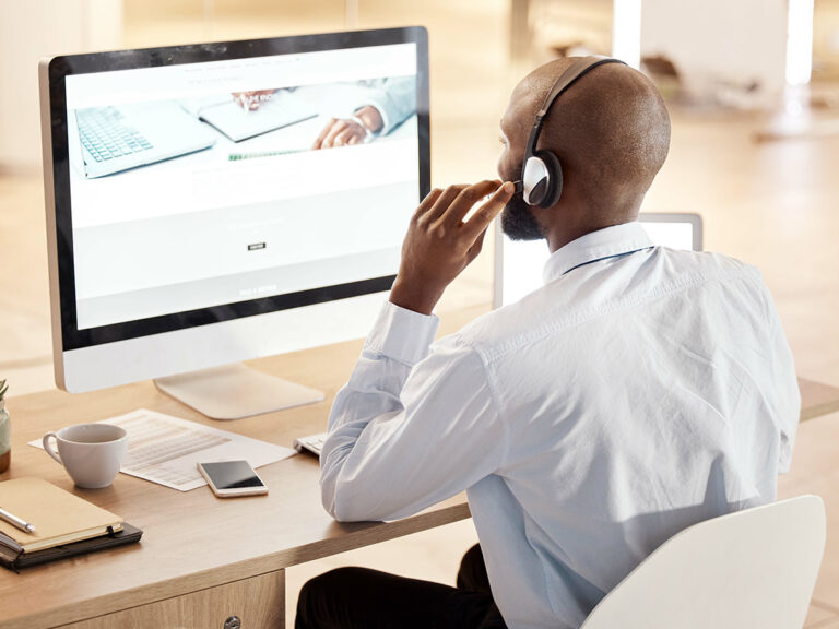 Man wearing headphones viewing monitor with notebook and laptop image explaining evergreen content strategy