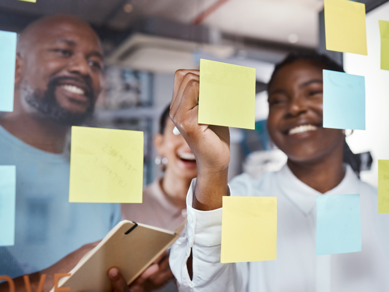 Three people organizing ideas on post-its to develop a strategic content plan using content pillars.