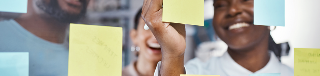 Three people organizing ideas on post-its to develop a strategic content plan using content pillars.