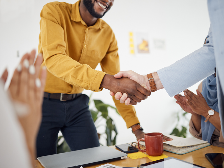 Two men shaking hands as customers applaud, representing positive Google Business reviews.