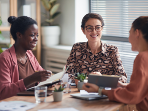 Three women collaborating on a strategy to attract new customers with new mover marketing.