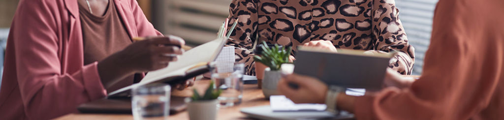 Three women collaborating on a strategy to attract new customers with new mover marketing.