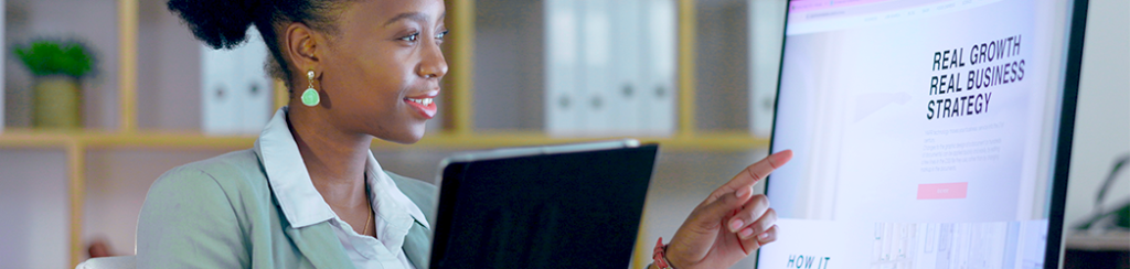 Woman viewing monitor and tablet showing real growth real business strategy, focused on brand storytelling.